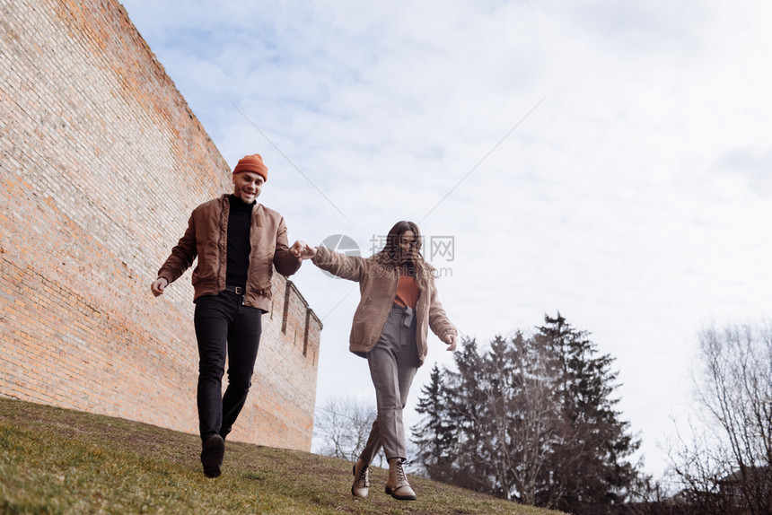 幸福的情侣在草地上牵手散步图片