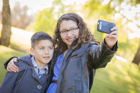 哥和姐在公园户外拍摄自己手机照片图片