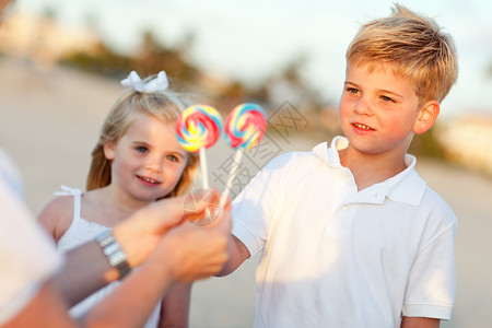 可爱的哥和妹挑选棒糖出他们的妈在海滩上图片