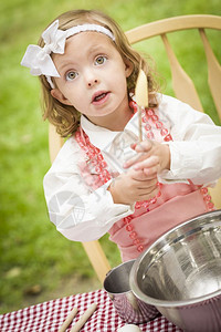 快乐可爱的小女孩玩厨师烹饪在她的粉红色服装图片