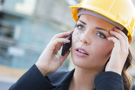 在建筑工地用手机戴硬帽的年轻忧心忡的女专业承包商图片