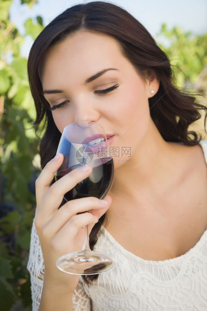年轻成女子在葡萄园里喝杯酒图片