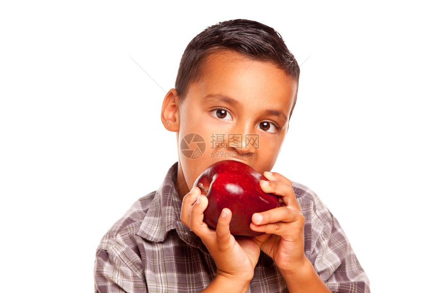 可爱的西班牙男孩吃一个大红苹果孤立在白色背景图片