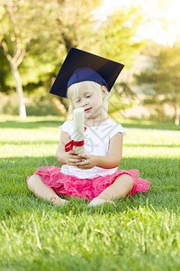 戴着毕业帽子可爱的小女孩持有毕业证书图片
