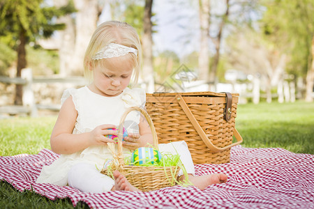 在公园野餐的毯子上给蛋壳绘画的小女孩图片