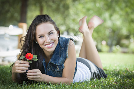 有吸引力的混合种族女孩肖像在露天草地上用花朵铺设图片