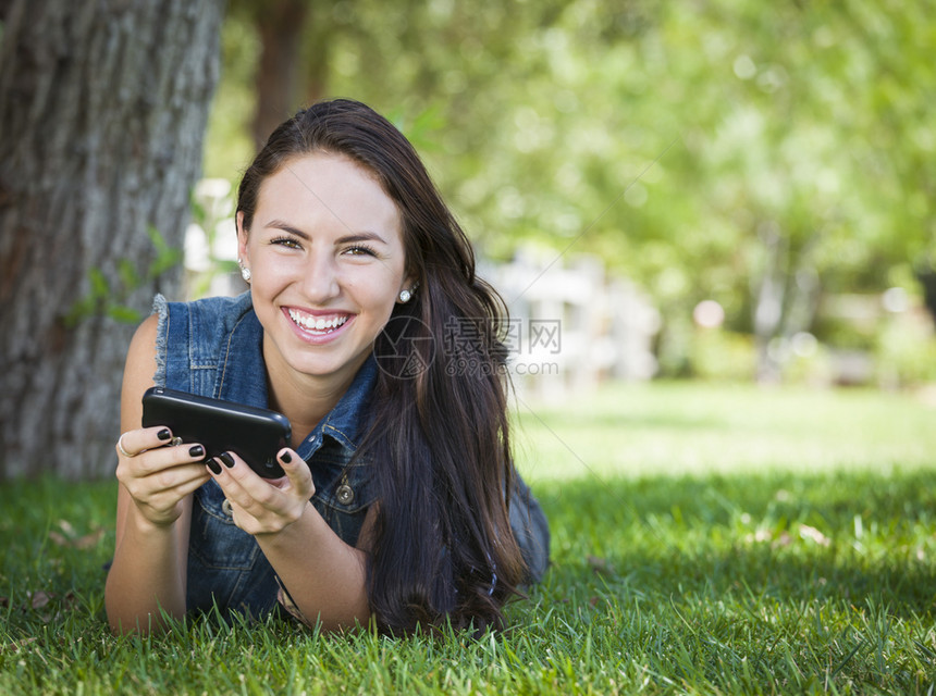 年轻女在外边的手机上发短信躺在草地上图片