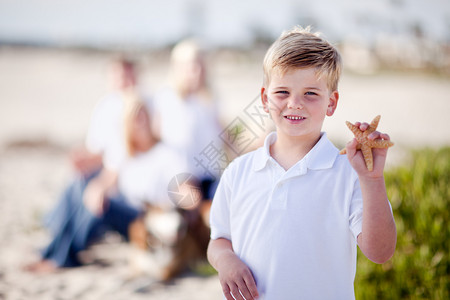 可爱的金发小男孩炫耀他的海星在滩上图片