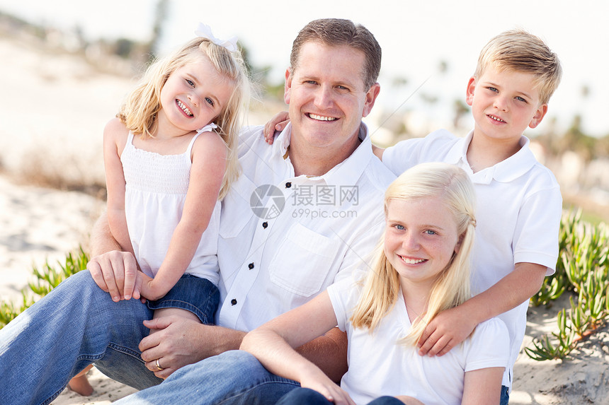 英俊的爸和他可爱孩子们坐在海滩上图片