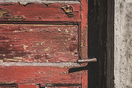 风化的红门紧闭着生锈的门把手和破碎的红漆关闭着门图片