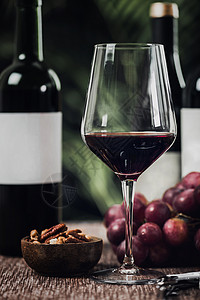 酒杯不同瓶红木碗里的坚果和新鲜葡萄图片