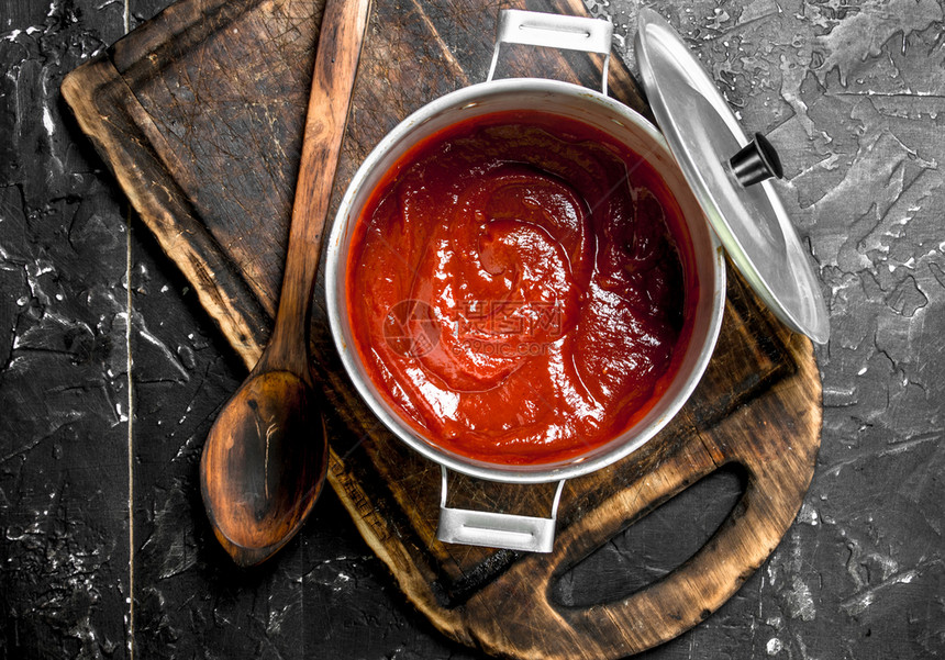 锅里的番茄酱在切削板上的锅里生锈背景图片