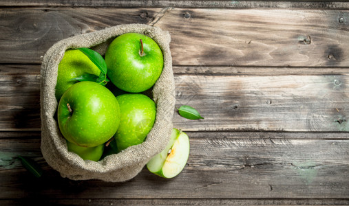 木苹果绿色苹果和切片在一个旧袋子里灰木底的色本绿苹果和切片在一个旧袋子里背景