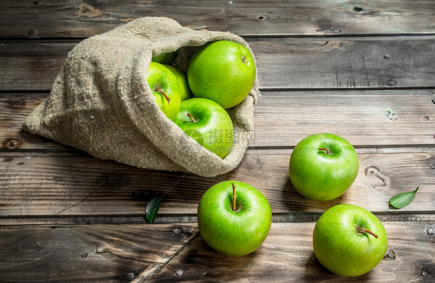 灰木本底的旧袋子里有多汁的绿苹果图片