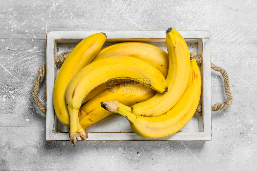 新鲜香蕉在木箱里白色生锈背景图片