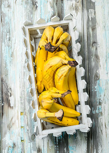 白色塑料篮子中的新鲜香蕉白色木制背景的新鲜香蕉图片