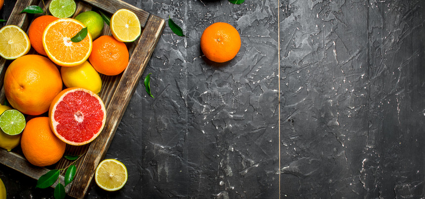 成熟的柑橘水果有叶子放在盘里黑色生锈背景放在盘子里图片