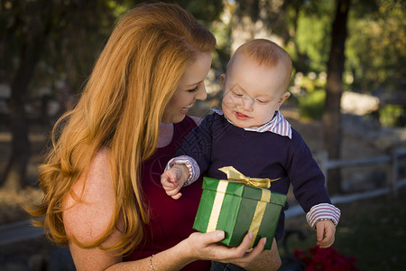 年轻母亲和婴儿抱着圣诞礼物图片