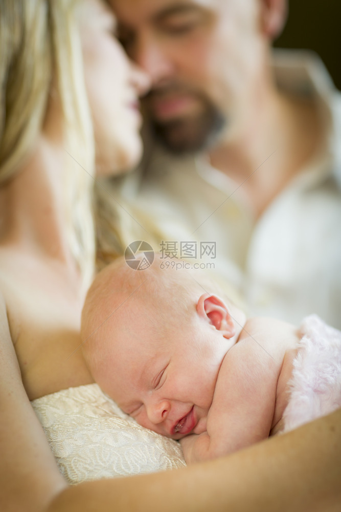 美丽的年轻夫妇把他们新生的睡着女婴抱在里面图片