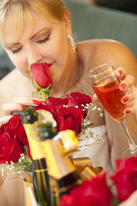 迷人的金发女郎在香槟旁边的镜子里闻到玫瑰香味图片
