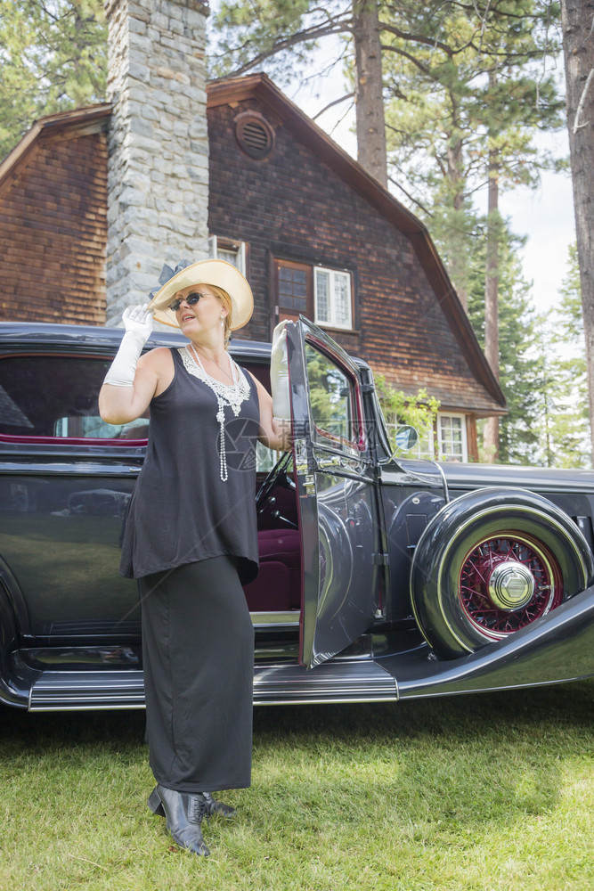 身着20年代服装的美女站在古董汽车附近图片