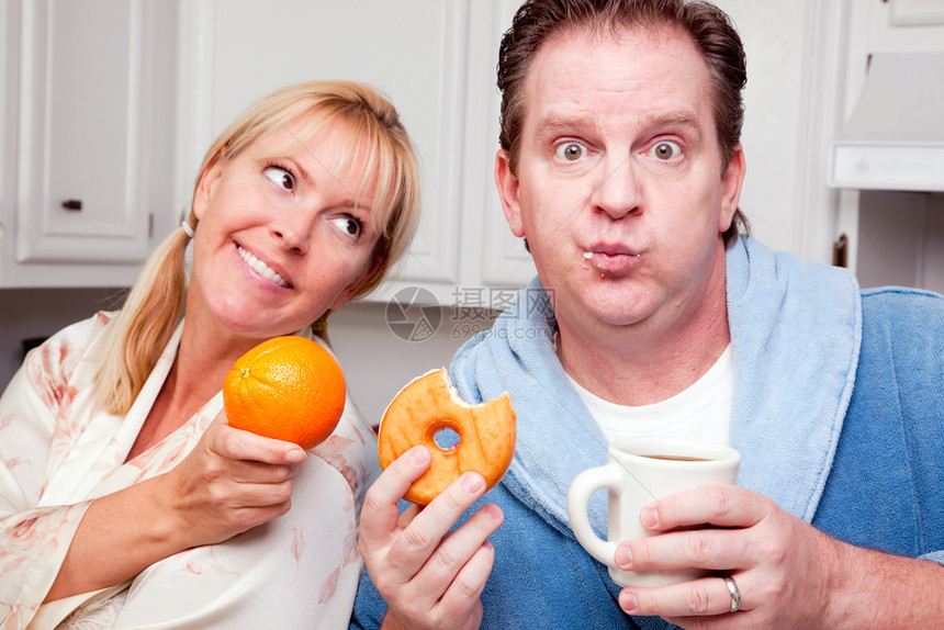 夫妻在厨房吃甜圈咖啡或健康水果图片