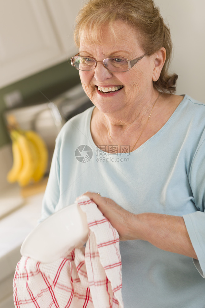 高龄成年女人在厨房的水槽里微笑着的烘干碗图片