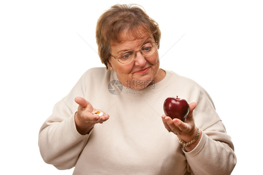 带着苹果和维他命的困惑高龄妇女孤立在白种背景上图片