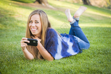 微笑的年轻女子在公园户外使用手机图片