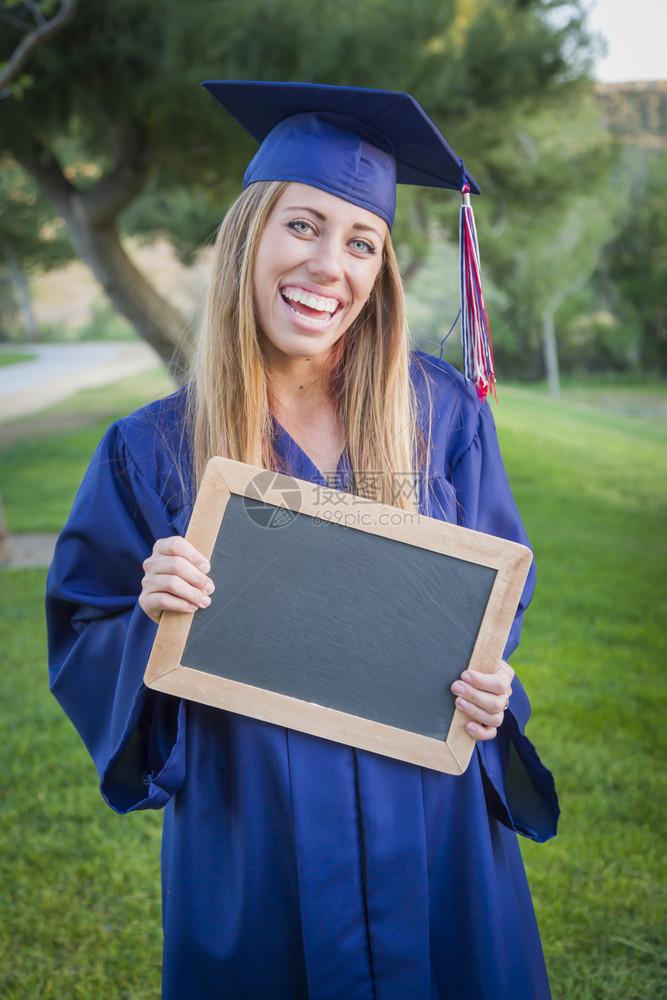 兴奋的年轻女子持有文凭和空白黑板在户外佩戴帽子和礼服图片