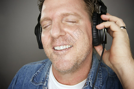 男子戴耳机在灰色背景下享受音乐男子戴耳机图片