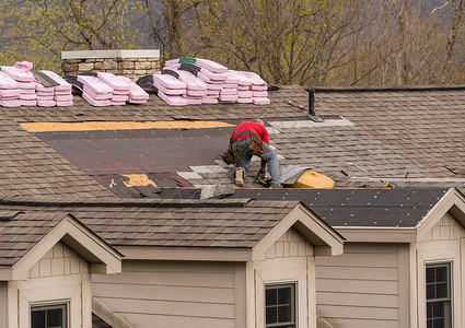 房顶承包商拆除旧瓷砖然后在市政楼屋顶上用新的闪光板替换房顶承包商将旧的闪光板从准备更换屋顶的上搬走背景