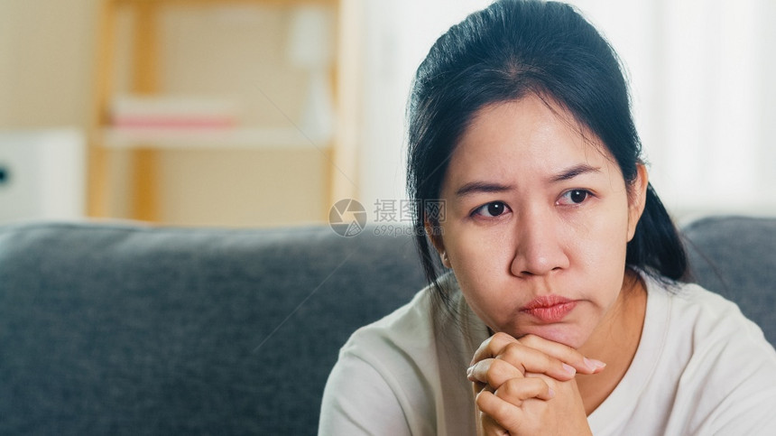 哭泣的亚洲女商人强调坐在沙发上头痛图片