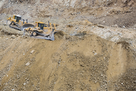 两辆挖土机拖拉在移动泥土背景图片