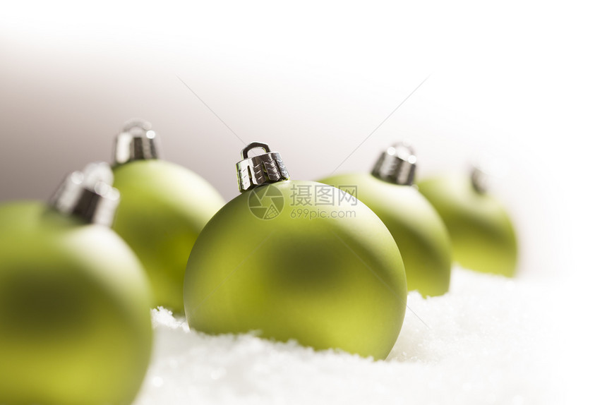 灰色背景的雪片上绿色圣诞装饰品顶部和右侧是白色的图片