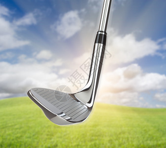 铬高尔夫俱乐部的铁与草地和蓝天空背景作对图片