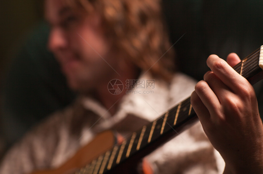 年轻的音乐家在戏剧照明下演奏他的音响吉图片