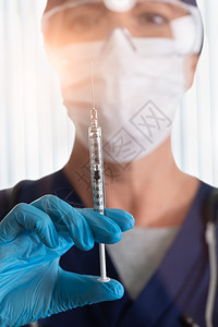 医生或护士戴疗面罩和护目镜手持装满药品的注射器图片