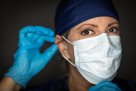女医生或护士佩戴外科手套上医疗面罩图片