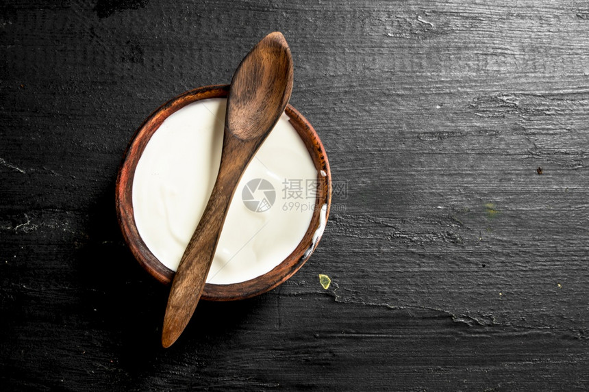 黑板上白的碗里和勺子一起的碗里天然酸奶图片