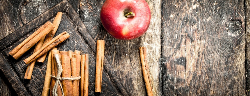 新鲜苹果和肉桂棒木制背景图片