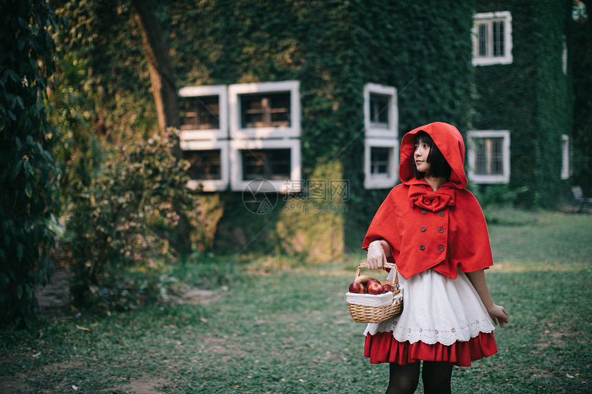 在绿树公园穿着小红色兜帽装饰的年轻女子肖像图片