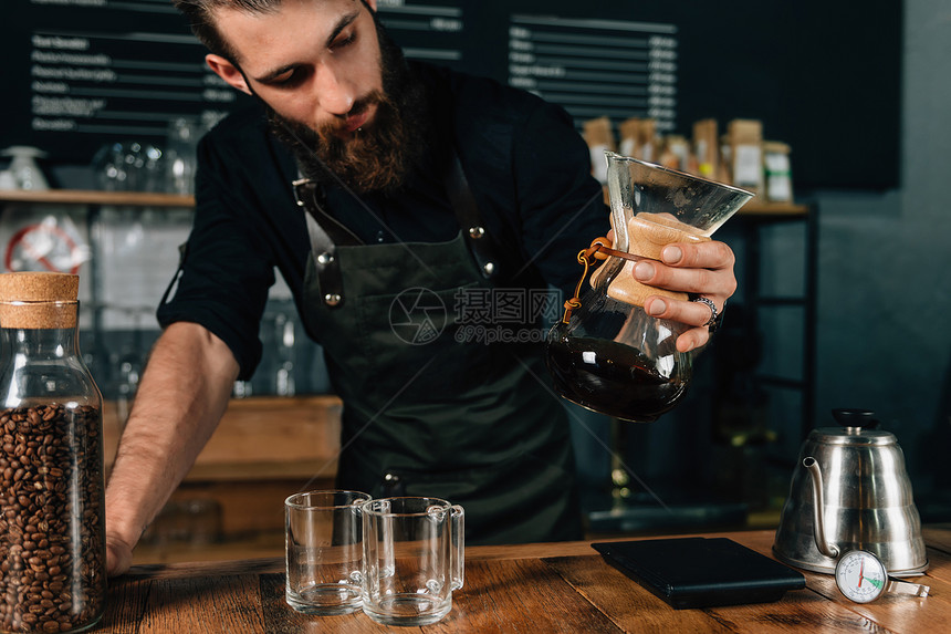年轻男咖啡师穿着深色制服看过滤咖啡制造商图片