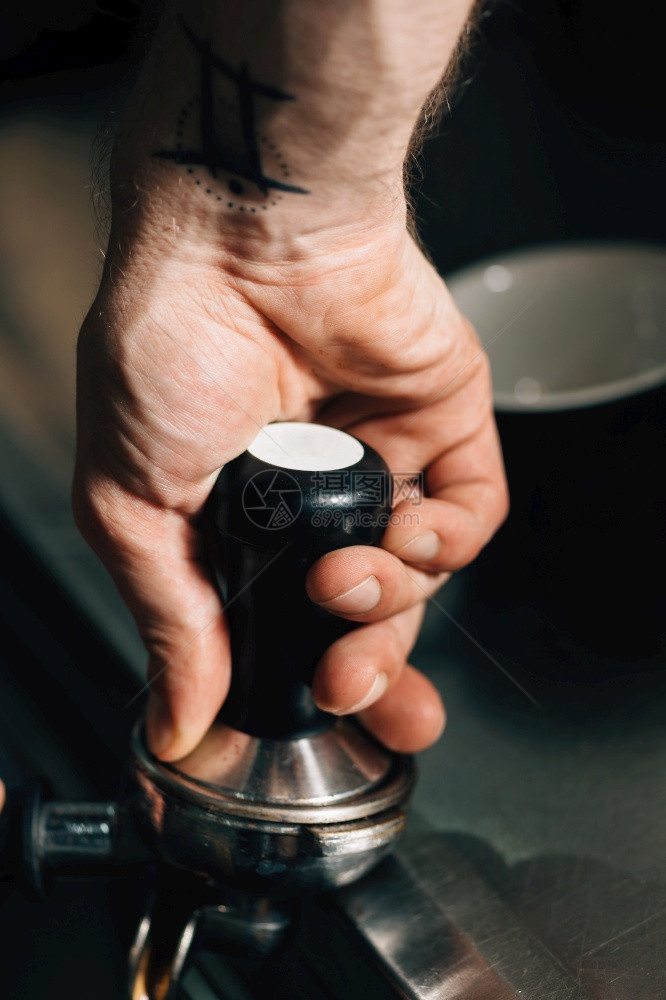 咖啡师用黑色手柄压咖啡图片