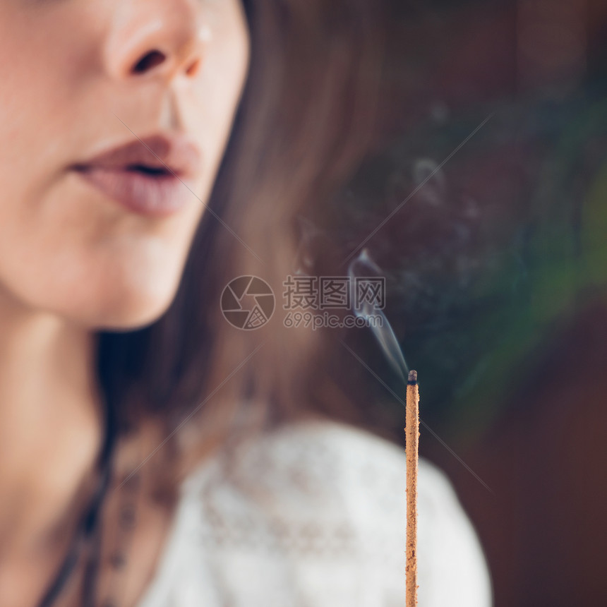 美丽的causin女孩吹烟从燃烧的香棒图片