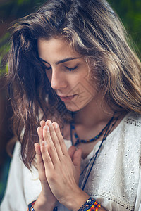 年轻女孩站在她的眼中紧地站着手握在祈祷的位置上手握在鼻孔的上背景图片