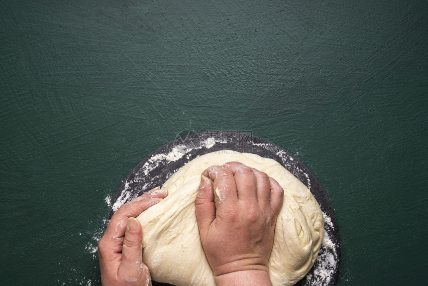 妇女手为披萨做面粉新鲜自家做的比萨饼面团在视图上方无法凝视的女人在白面粉团中打斗图片