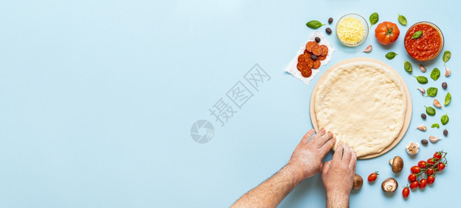 一步地做比萨饼男人和双手伸展在比萨石头上的面团披萨成分直接放在桌子上图片
