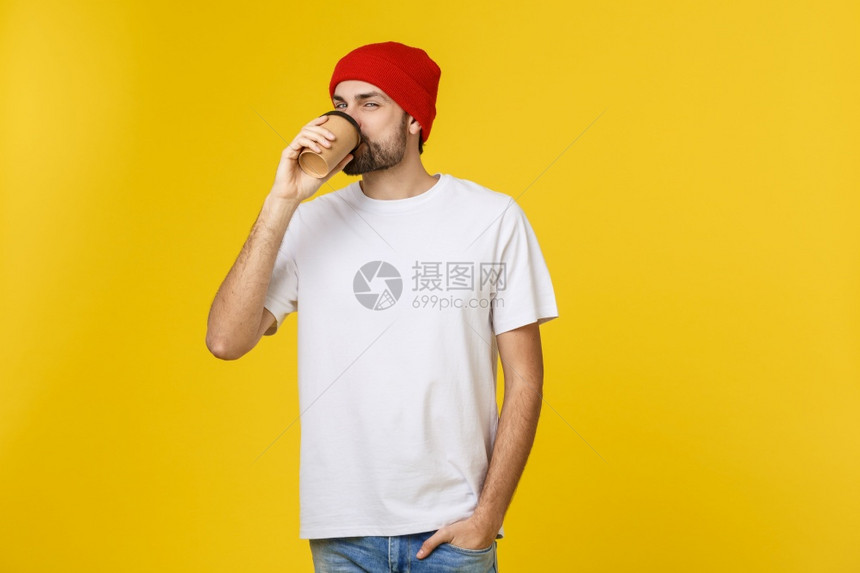 年轻时装男拿着一杯咖啡隔黄色背景的咖啡图片
