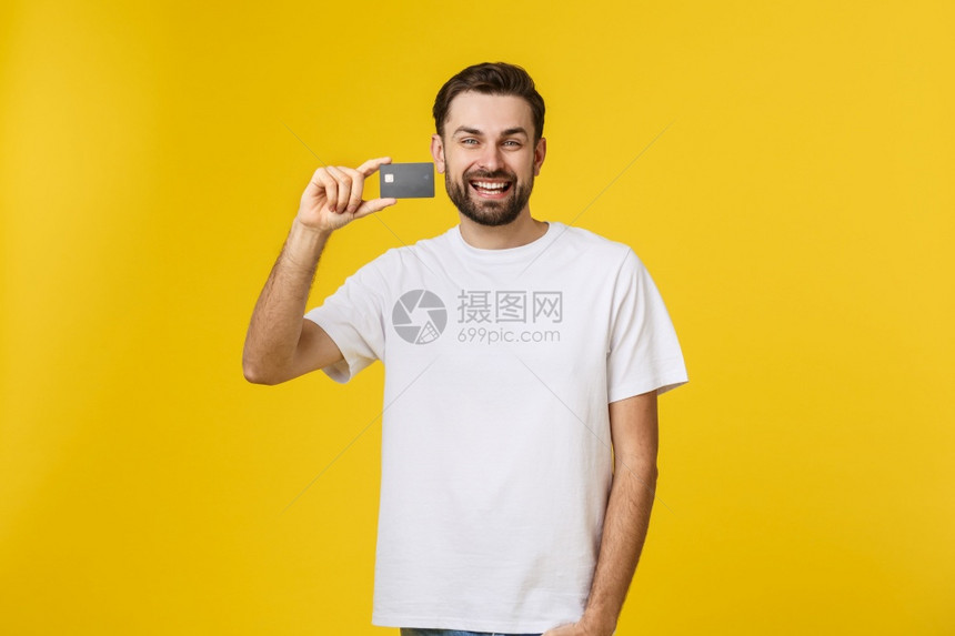 笑的年轻男子展示在黄色背景上被孤立的信用卡笑的年轻男子展示在黄色背景上被孤立的信用卡图片